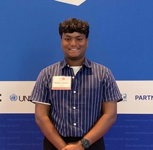 Ahillan Kumar standing in front of a blue background