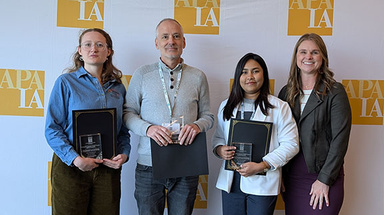 Four individuals accepting the award, standing in front of an APA background.