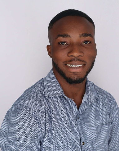 Headshot of Ibrahim Suleman, wearing a blue shirt with a white background