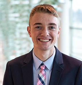 Isaac Smith smiling and wearing blue suit and a tie. 
