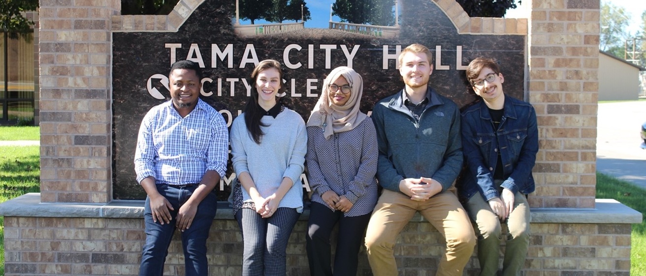 Five urban planning students sitting in front of Tama City Hall sign
