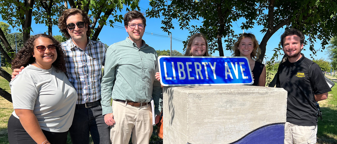 Clinton IA Liberty Square capstone team of students standing outside with a "Liberty Square" street sign