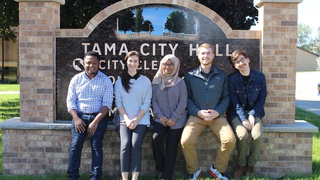 Five urban planning students sitting in front of Tama City Hall sign